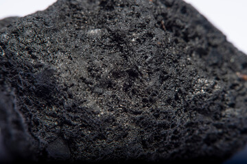 Blurred black background in soft focus with hard coal at high magnification. An image on the theme of geology and the extraction of minerals and natural fuels.