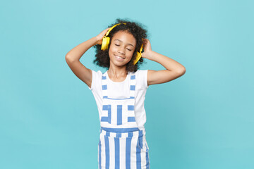 Cute little african american kid girl 12-13 years old in striped clothes isolated on blue...