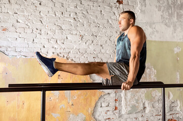 fitness, sport, bodybuilding and people concept - young man doing abdominal exercise on parallel...