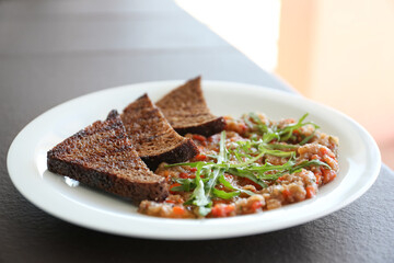 Delicious salad with roasted eggplant and bread on plate