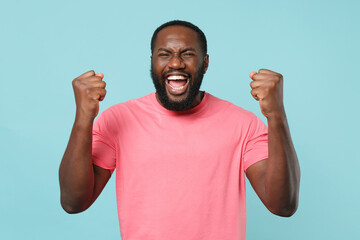 Joyful young african american man guy in casual pink t-shirt posing isolated on pastel blue...