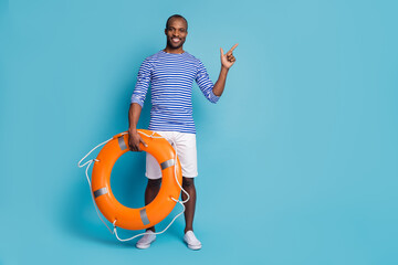 Fototapeta premium Full length body size view of his he nice attractive cheerful cheery guy rescuer holding in hand rubber lifesaver showing copy space isolated over bright vivid shine vibrant blue color background