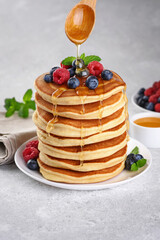 Pancakes with fresh berry and honey on gray background. Healthy breakfast.
