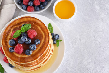 Pancakes with fresh berry and honey on gray background. Healthy breakfast.