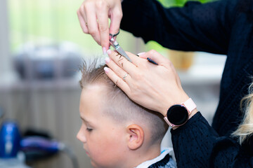 Obraz na płótnie Canvas Serious school boy ready getting trendy haircut from expirienced barber at fashionable hairdressing salon.