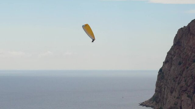 This stock video shows two person paragliding over the sea. Cinematic tracking shot of paraglider, flying over tropical sea coast.