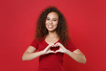 Smiling young african american woman girl in casual t-shirt posing isolated on red background...