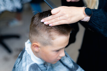 Close up caucasian american pretty school boy trendy haircut at bright modern barbershop.