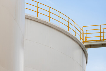 white steel tank with yellow handrial in chemical plant. big metal silo in factory with blue sky background.