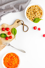 Vegetarian meal. Chickpeas and carrot in bowls on white table top view copy space