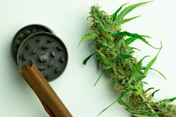 Cannabis bud with grinder and blunt or joint flat lay top view. Marijuana smoke accessories, white...