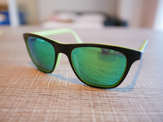 Black sunglasses with mercury lenses are placed on the table.