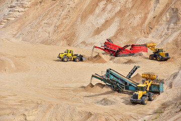 Wheel front-end loader loads sand into a dump truck. Heavy machinery in the mining quarry,...