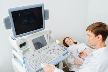 Attentive doctor performing ultrasound scan on a young female patient.