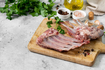 Lamb meat. Lamb ribs on a wooden chopping Board on the light gray kitchen table. Raw meat of a young lamb on the table