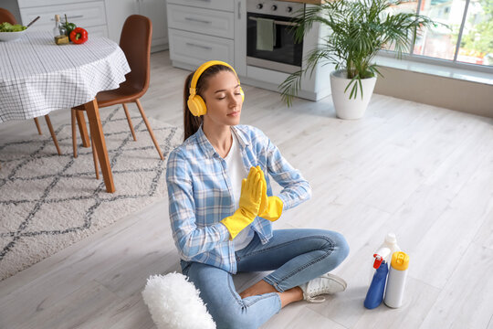 Beautiful young woman meditating during cleaning of kitchen