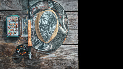 Fishing equipment. A rod, a box of flies and a hat.