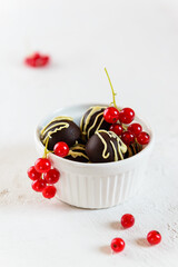Homemade chocolates garnished with red currants in a white bowl. Sugar, lactose, gluten free.