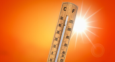 Thermometer against orange background with hot summer sun. Heat wave concept.