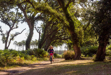 cute little girl riding a bicycle in a cork oak forest