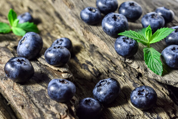 Fresh, juicy, raw blueberries and mint leaves on an old, vintage wooden background. Summer berries, healthy snack.