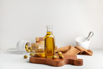 Bottle of tasty olive oil and bread on white background