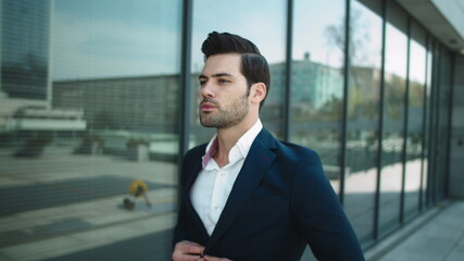 Portrait businessman walking in suit. Man checking time on wrist watch outside