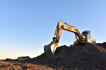Excavator working on earthmoving at open pit mining. Yellow Backhoe digs sand and gravel in quarry....