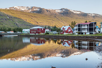 Fototapeta premium Village of Seydisfjordur, Iceland, known for its traditional architecture, reflected in a lake.