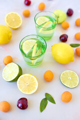 Tasty lemonade or mojito cocktail with lemon and lime. Refreshing drink or beverage. Colorfull backdrop with fruits and berries