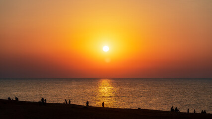 Naklejka na ściany i meble Silhouettes of people on beach at sunset
