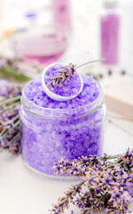 Obraz na płótnie Canvas Lavender violet sea salt with lavender flowers. Lavender bath products Aromatherapy treatment on white wooden background. Skincare spa beauty bath cosmetic products for relax.
