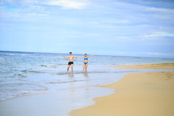 man and woman in bathing suits on beach by sea.