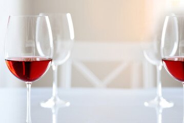 Glasses with red wine on a white table in a white light interior.
