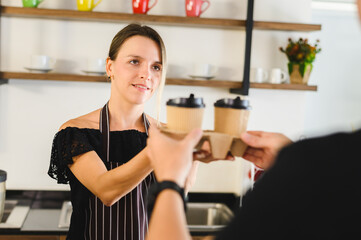 Female barista giving coffee in cardboard cups,concept: environmental protection, nature conservation, recycle.