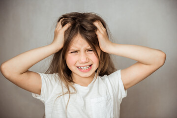 Cute girl suffering from headache on gray background