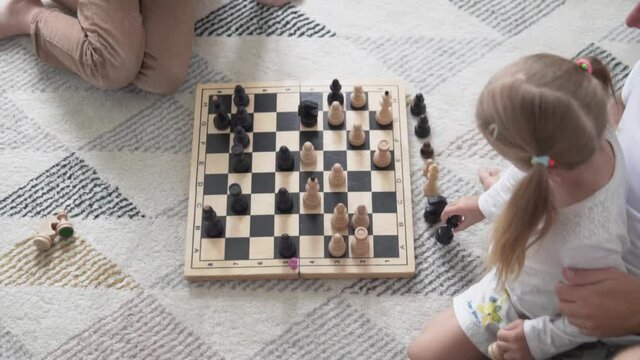 Dad plays chess with the kids at home. Family day off playing chess