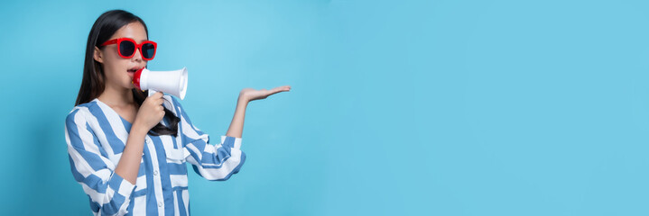 Beautiful Asian woman wearing red glasses holding white megaphone to yell and announce for present product , present big sell in long copy space