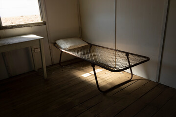 Old wire camp bed in abandoned shearers quarters building.