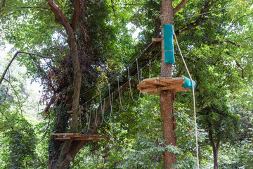 View of the adventure park with obstacles on the trees. Forest barriers to family satisfaction. Adrenaline park in nature