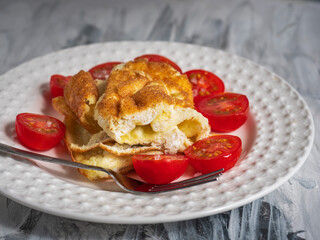 Quick breakfast with scrambled eggs and sliced tomato on a white plate on a black and white background