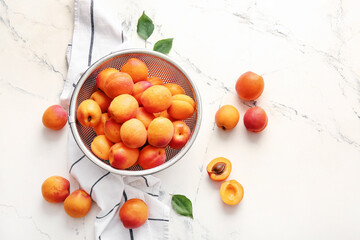 Colander with tasty ripe apricots on white background