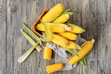 Box with fresh corn cobs on table