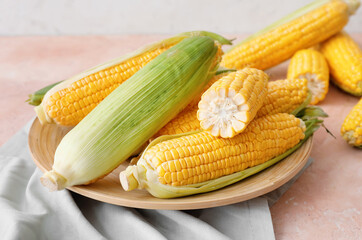 Plate with fresh corn cobs on table