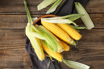 Bowl with fresh corn cobs on table