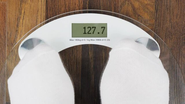 Overweight on bathroom scales digital display with an inscription WTF. Concept of tackling overweight and obesity. A woman steps on the scales to check her weight. Close-up view