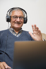 Modern elderly man siting at home and having online video call