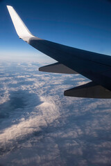 Wing tip of plane over the cloud during flight. The winglet shines in the sun