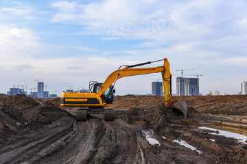 Obraz premium Excavator during excavation at construction site. Backhoe on Earthworks. Heavy Construction Equipment Machines in Action. Big Digger Digging the Foundation House. Soft focus