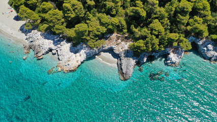 Aerial drone photo of secluded rocky cove near turquoise pebble paradise beach of Kastani covered with pine trees, Skopelos island, Sporades, Greece